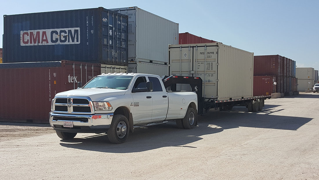 A white truck pulling a trailer full of cargo.