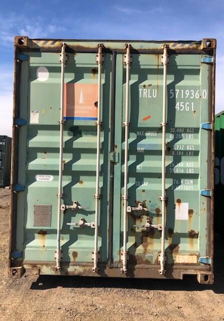 A green container sitting on top of a field.